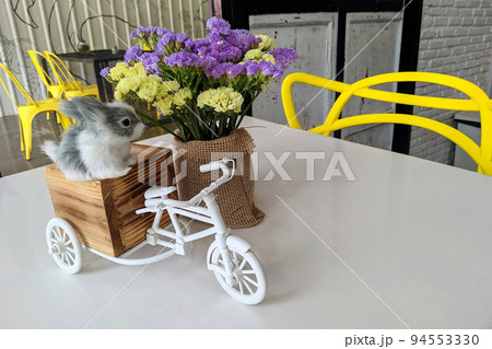 The dining table decorations include rabbit doll, flower pots and simulation tricycles. 94553330
