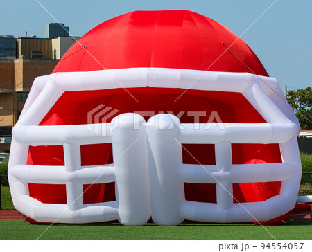 Large blow up red and white football helmet for players to enter the game through Large blow up red and white football helmet for players to enter the game through 94554057