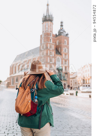 Famous cathedral in sun light, Tourist happy woman on Market Square in Krakow, Traveling Europe in autumn. St. Marys Basilica, no face 94554872
