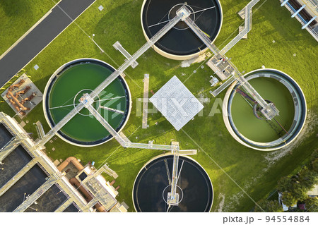Aerial view of modern water cleaning facility at urban wastewater treatment plant. Purification process of removing undesirable chemicals, suspended solids and gases from contaminated liquid Aerial view of modern water cleaning facility at urban wastewater treatment plant. Purification process of removing undesirable chemicals, suspended solids and gases from contaminated liquid 94554884
