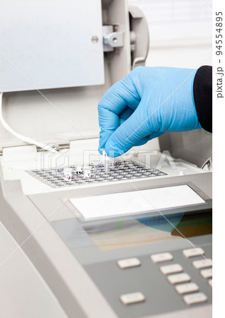 Closeup of a scientist hand while working at the laboratory with a thermal cycler. Polymerase chain reaction technique. PCR technique 94554895