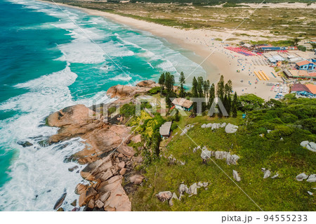 Popular Joaquina Beach with rocks and ocean with waves in Brazil. Aerial view Popular Joaquina Beach with rocks and ocean with waves in Brazil. Aerial view 94555233