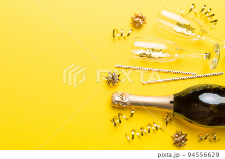 Champagne bottle, glitter and straws on color background. top view. Hilarious, christmas and birthday celebration Champagne bottle, glitter and straws on color background. top view. Hilarious, christmas and birthday celebration 94556629