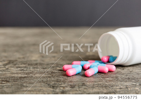 plastic medicine bottle with capsules of pills on colored background. Online pharmacy. Painkiller medicine and antibiotic drug resistance concept. Pharmaceutical industry plastic medicine bottle with capsules of pills on colored background. Online pharmacy. Painkiller medicine and antibiotic drug resistance concept. Pharmaceutical industry 94556775