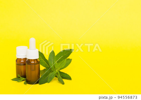 Natural Mint Essential Oil in a Glass Bottle. organic cosmetics with herbal extracts of mint on colored background Natural Mint Essential Oil in a Glass Bottle. organic cosmetics with herbal extracts of mint on colored background 94556873