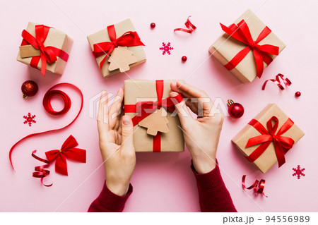 Woman hands holding gift box, preparing surprise for holiday, top view, Christmas and New Year concept Woman hands holding gift box, preparing surprise for holiday, top view, Christmas and New Year concept 94556989