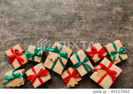 wrapped christmas or other holiday handmade present in paper with colored ribbon. Present box, decoration of gift on colourfull table, top view with copy space 94557062
