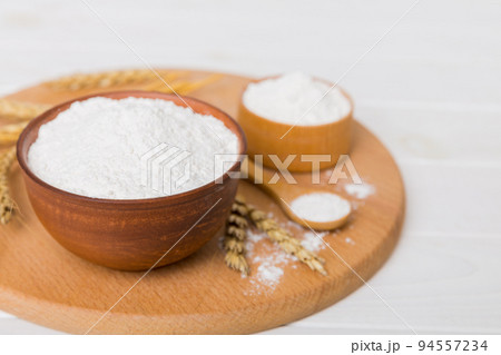 Flat lay of Wheat flour in wooden bowl with wheat spikelets on colored background. world wheat crisis Flat lay of Wheat flour in wooden bowl with wheat spikelets on colored background. world wheat crisis 94557234