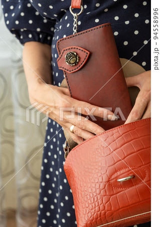 Woman takes a brown natural leather wallet out of her purse. Woman takes a brown natural leather wallet out of her purse. 94558996