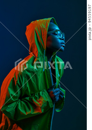 Young fashion woman in raincoat in neon light 94559197