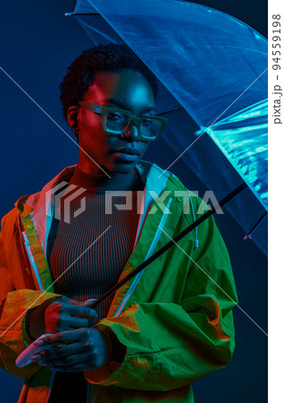Hipster woman in raincoat with umbrella in neon light 94559198
