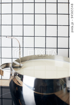 The process of making yogurt. Milk is heated and fermented by bacteria. Milk in a pot on the stove. Vertical photo. The process of making yogurt. Milk is heated and fermented by bacteria. Milk in a pot on the stove. Vertical photo. 94565548