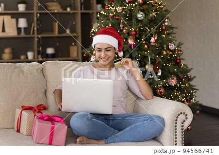 Indian girl in Santa hat using laptop for online shopping 94566741