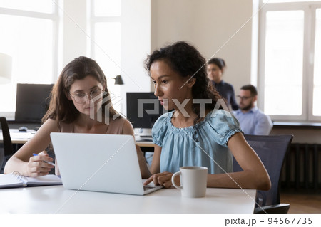 Focused intern, student consulting corporate teacher, using laptop 94567735