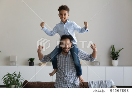 Portrait of happy Young African American dad playing with son. 94567898