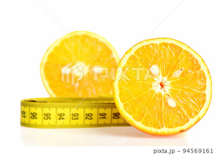 Halves of orange fruit together with folded yellow measure tape 94569161