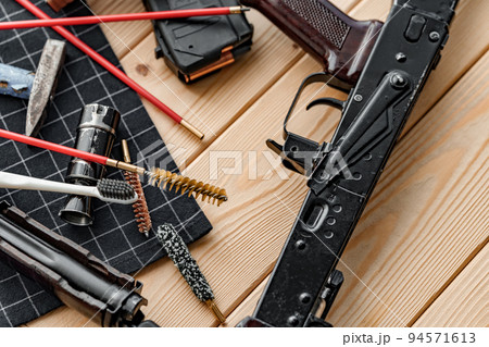 Black disassembled shotgun and cleaning tools on wooden table . Black disassembled shotgun and cleaning tools on wooden table . 94571613