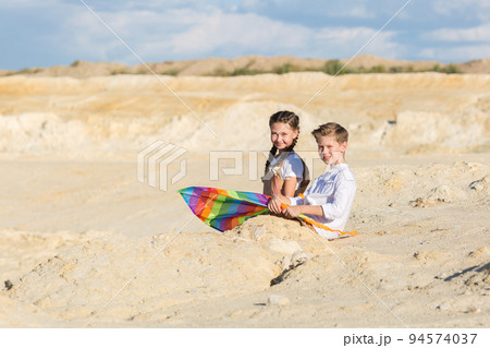 Children best friends sitting with a kite in nature after school 94574037