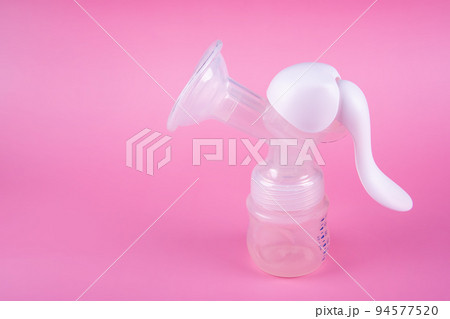 Manual breast pump on pink paper background. Device for increasing milk supply for breastfeeding mother. Maternity and baby care concept Manual breast pump on pink paper background. Device for increasing milk supply for breastfeeding mother. Maternity and baby care concept 94577520