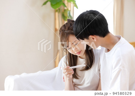 妊娠検査薬を見る夫婦 94580329