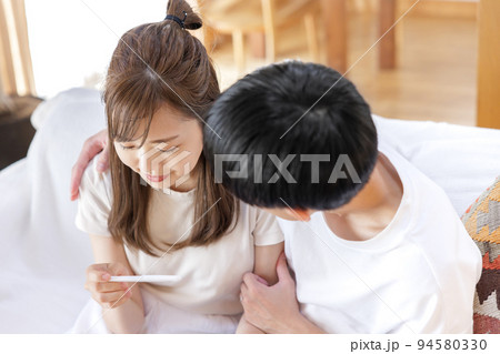 妊娠検査薬を見る夫婦 94580330