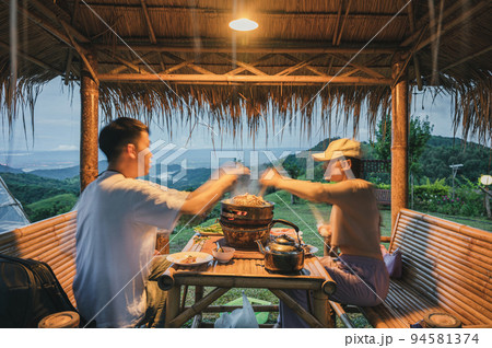 Young couple grilling thai pork barbecue on pan in the hut along with a view of mist on hill 94581374