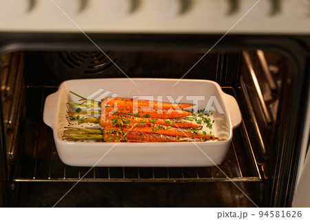 Fried carrots with green herbs on a ceramic form,in the oven, selective focus. Fried carrots with green herbs on a ceramic form,in the oven, selective focus. 94581626