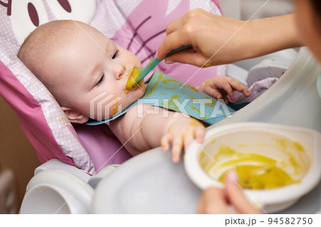 baby girl eating with spoon in kitchen baby girl eating with spoon in kitchen 94582750