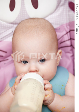 baby 6 months old sits and drinks milk from a bottle baby 6 months old sits and drinks milk from a bottle 94582751