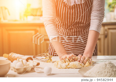 Woman hands kneading dough on kitchen table 94582944