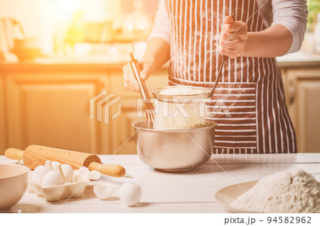 Young woman holding bowl with dough and whisk, closeup Young woman holding bowl with dough and whisk, closeup 94582962