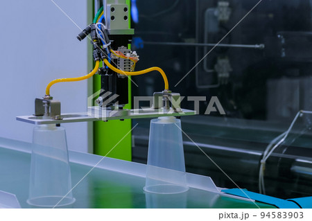 Automatic robotic production line with moving plastic cups on conveyor belt 94583903