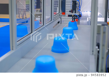 Automatic robotic production line with moving plastic blue pots on conveyor belt Automatic robotic production line with moving plastic blue pots on conveyor belt 94583952