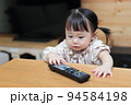 テレビのリモコンをいたずらする1歳の女の子 94584198