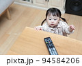 テレビのリモコンをいたずらする1歳の女の子 94584206