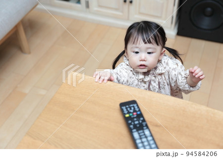 テレビのリモコンをいたずらする1歳の女の子 94584206