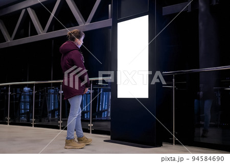 White screen concept - woman looking at blank interactive white display kiosk 94584690