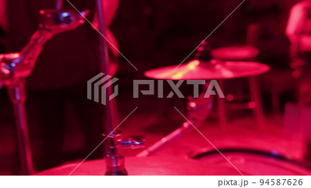 Unrecognizable musician hands hitting drum plates in recording studio. Close up of drummer hands performing solo with drumsticks. Attractive artist playing on drum kit indoor in red light Unrecognizable musician hands hitting drum plates in recording studio. Close up of drummer hands performing solo with drumsticks. Attractive artist playing on drum kit indoor in red light 94587626