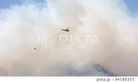 Wildfire Service Helicopter flying over BC Forest Fire and Smoke on the mountain near Hope 94588355