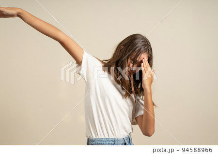 Young Hispanic teenage girl striking a funny pose on a beige studio background 94588966