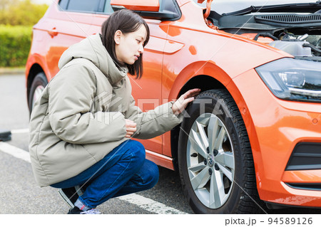 車のトラブルで困った様子の若い女性ドライバー 94589126