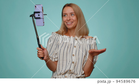 Girl blogger take selfie on mobile phone selfie stick communicate video call online with subscribers Girl blogger take selfie on mobile phone selfie stick communicate video call online with subscribers 94589676