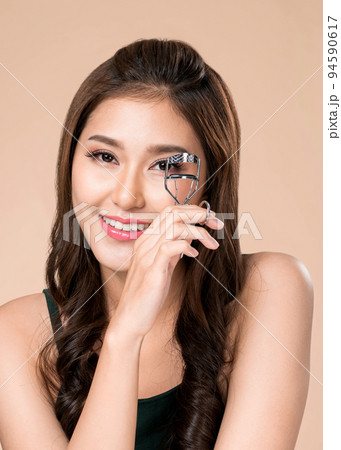 closeup ardent female model with flawless beautiful skin using eyelash curler. 94590617