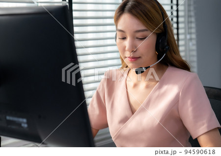 Competent female operator working on computer and while talking with clients. 94590618