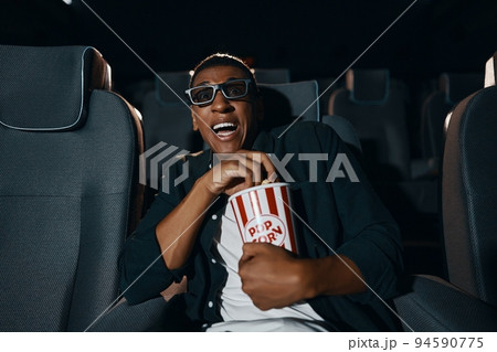 The man came to the meaning of the movie in the cinema with popcorn. 94590775