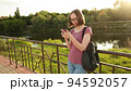 Woman using smartphone standing outdoors on the bridge.  94592057