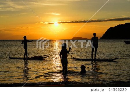 夕暮れの逗子海岸、陽射しを浴びてSUPヨガを楽しむ若者たちと犬の散歩をする女の子 94596229
