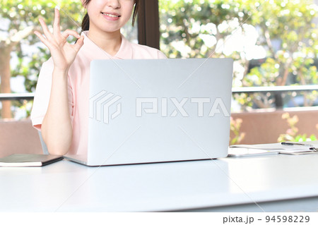 パソコンの前でOKをする女性スタッフ パソコンの前でOKをする女性スタッフ 94598229