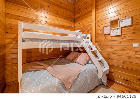 Children bedroom with bunk bed and wooden walls. Cozy and comfortable cottage interior. 94601129