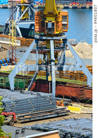 industrial seaport infrastructure - sea, cranes and metal workpieces, bundles of wire, railcars on railroad, concept of marine cargo transportation industrial seaport infrastructure - sea, cranes and metal workpieces, bundles of wire, railcars on railroad, concept of marine cargo transportation 94601807